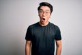 Young handsome chinese man wearing black t-shirt and glasses over white background afraid and shocked with surprise expression, Royalty Free Stock Photo