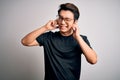 Young handsome chinese man wearing black t-shirt and glasses over white background covering ears with fingers with annoyed Royalty Free Stock Photo