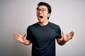 Young handsome chinese man wearing black t-shirt and glasses over white background crazy and mad shouting and yelling with Royalty Free Stock Photo