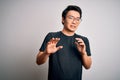 Young handsome chinese man wearing black t-shirt and glasses over white background disgusted expression, displeased and fearful