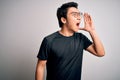 Young handsome chinese man wearing black t-shirt and glasses over white background shouting and screaming loud to side with hand Royalty Free Stock Photo