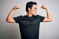 Young handsome chinese man wearing black t-shirt and glasses over white background showing arms muscles smiling proud Royalty Free Stock Photo