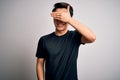 Young handsome chinese man wearing black t-shirt and glasses over white background smiling and laughing with hand on face covering Royalty Free Stock Photo