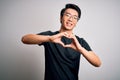 Young handsome chinese man wearing black t-shirt and glasses over white background smiling in love doing heart symbol shape with Royalty Free Stock Photo