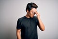 Young handsome chinese man wearing black t-shirt and glasses over white background tired rubbing nose and eyes feeling fatigue and Royalty Free Stock Photo