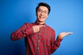 Young handsome chinese man wearing casual shirt and glasses over blue background amazed and smiling to the camera while presenting Royalty Free Stock Photo