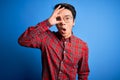 Young handsome chinese man wearing casual shirt and glasses over blue background doing ok gesture shocked with surprised face, eye Royalty Free Stock Photo