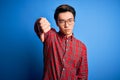 Young handsome chinese man wearing casual shirt and glasses over blue background looking unhappy and angry showing rejection and Royalty Free Stock Photo