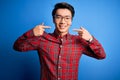 Young handsome chinese man wearing casual shirt and glasses over blue background smiling cheerful showing and pointing with Royalty Free Stock Photo