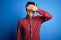 Young handsome chinese man wearing casual shirt and glasses over blue background smiling and laughing with hand on face covering Royalty Free Stock Photo