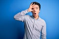 Young handsome chinese man wearing casual shirt standing over isolated blue background doing ok gesture shocked with surprised Royalty Free Stock Photo