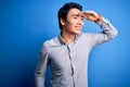 Young handsome chinese man wearing casual shirt standing over isolated blue background very happy and smiling looking far away Royalty Free Stock Photo