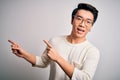 Young handsome chinese man wearing casual t-shirt and glasses over white background smiling and looking at the camera pointing Royalty Free Stock Photo