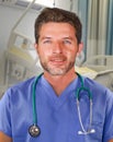 Young handsome and confident medicine doctor posing cheerful on blue scrubs and stethoscope on his neck smiling happy isolated on Royalty Free Stock Photo