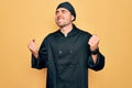 Young handsome cooker man with blue eyes wearing uniform and hat over yellow background very happy and excited doing winner Royalty Free Stock Photo