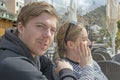 Young handsome couple sit in cafe and squint in stark sunshine