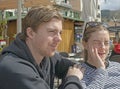 Young handsome couple sit in cafe and squint in stark sunshine