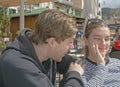 Young handsome couple sit in cafe and squint in stark sunshine