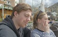 Young handsome couple sit in cafe and squint in stark sunshine