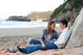 Young handsome couple sitting on beach. Royalty Free Stock Photo