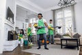 Young handsome crazy black-skinned cleaning service man in uniform, having fun wearing headphones, listening to music Royalty Free Stock Photo