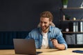 Young handsome curly smiling man with long hair in home office holding credit card and using laptop. Online shopping Royalty Free Stock Photo