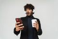 Young surprised indian man in headphones with coffee and phone