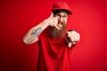 Young handsome delivery man wearing glasses and red cap over isolated background smiling doing talking on the telephone gesture Royalty Free Stock Photo