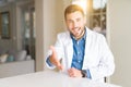 Young handsome doctor man at the clinic smiling friendly offering handshake as greeting and welcoming Royalty Free Stock Photo