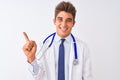 Young handsome doctor man wearing stethoscope over isolated white background with a big smile on face, pointing with hand and Royalty Free Stock Photo