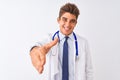 Young handsome doctor man wearing stethoscope over isolated white background smiling friendly offering handshake as greeting and Royalty Free Stock Photo