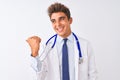 Young handsome doctor man wearing stethoscope over isolated white background smiling with happy face looking and pointing to the Royalty Free Stock Photo