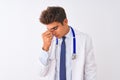Young handsome doctor man wearing stethoscope over isolated white background tired rubbing nose and eyes feeling fatigue and Royalty Free Stock Photo
