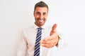 Young handsome elegant business man over isolated background smiling friendly offering handshake as greeting and welcoming Royalty Free Stock Photo