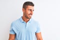 Young handsome elegant man wearing blue t-shirt over isolated background looking away to side with smile on face, natural Royalty Free Stock Photo