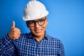 Young handsome engineer latin man wearing safety helmet over isolated blue background doing happy thumbs up gesture with hand Royalty Free Stock Photo