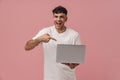 Young handsome enthusiastic man holding laptop and pointing on it