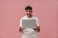 Young handsome enthusiastic man with opened mouth holding laptop