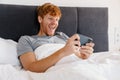 Young handsome enthusiastic redhead man in gray t-shirt playing mobile game