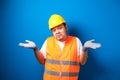 Young handsome fat asian worker man wearing orange safety vest uniform and helmet clueless and confused expression with arms and Royalty Free Stock Photo