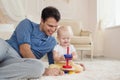 Young handsome father and cute son play building kit sitting on a carpet in children room