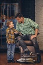 Young handsome father and his little stylish son at barbershop waiting for barber