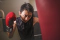 Young handsome and fierce teenager boy doing fight workout punching heavy bag looking cool and badass at fitness club training