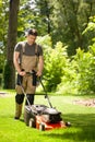 Handsome gardener waring brown overall and mowing the grass Royalty Free Stock Photo