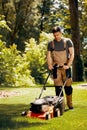 Handsome gardener waring brown overall and mowing the grass Royalty Free Stock Photo