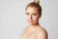 Young handsome girl with blonde hair fixed behind, big eyes, thick eyebrows and naked shoulders smiling on gray Royalty Free Stock Photo