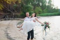 Young handsome groom holds his bride in his arms on the beach with a big bouquet of beautiful flowers Royalty Free Stock Photo