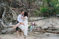 Young handsome groom holds his bride in his arms on the beach with a big bouquet of beautiful flowers Royalty Free Stock Photo