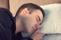 Young handsome guy is asleep wearing black t-shirt. Close up portrait. Day rest, Siesta. yellow ear plugs in the ears of men