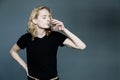 Young handsome guy in a black T-shirt with long blonde hair drinks clear water from a glass